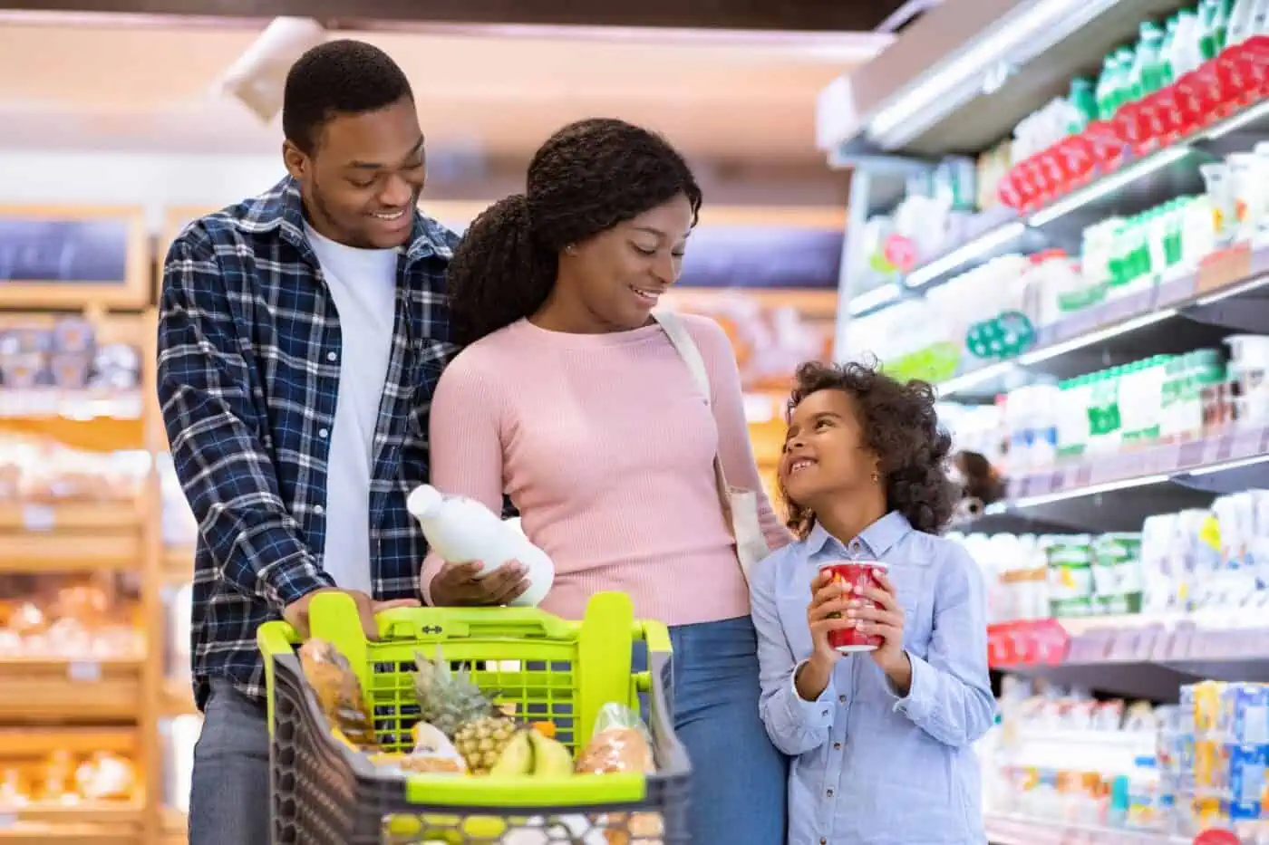 A family of three is grocery shopping in the dairy aisle